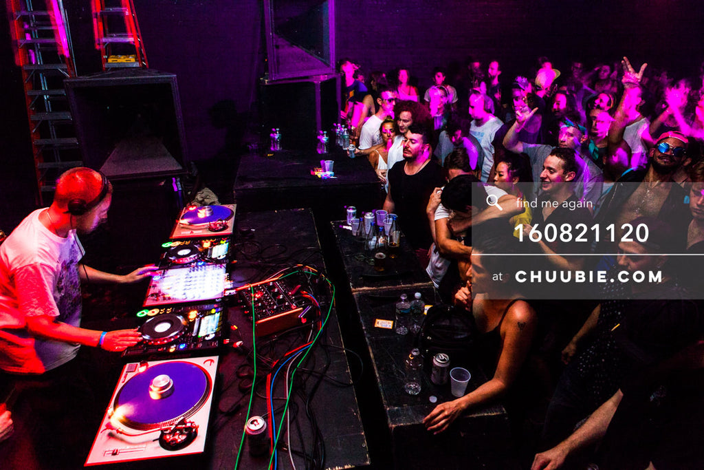 160821120 | 
Side view: Joy Orbison (Peter O'Grady) DJing to a packed dance floor crowd. Ambient red and pink... | Team Chuubie
