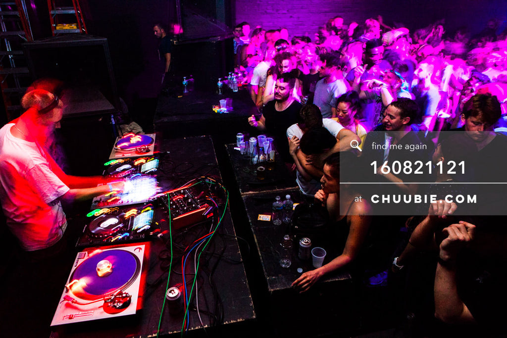 160821121 | 
Side view: Joy Orbison (Peter O'Grady) DJing to a packed dance floor crowd. Ambient red and pink... | Team Chuubie