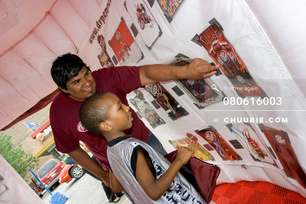 080613003 | 
Dr. Pepper ambassador shows young boy one of the contest finalist art entries.
āDr. PepperĀ Sabr... | Team Chuubie