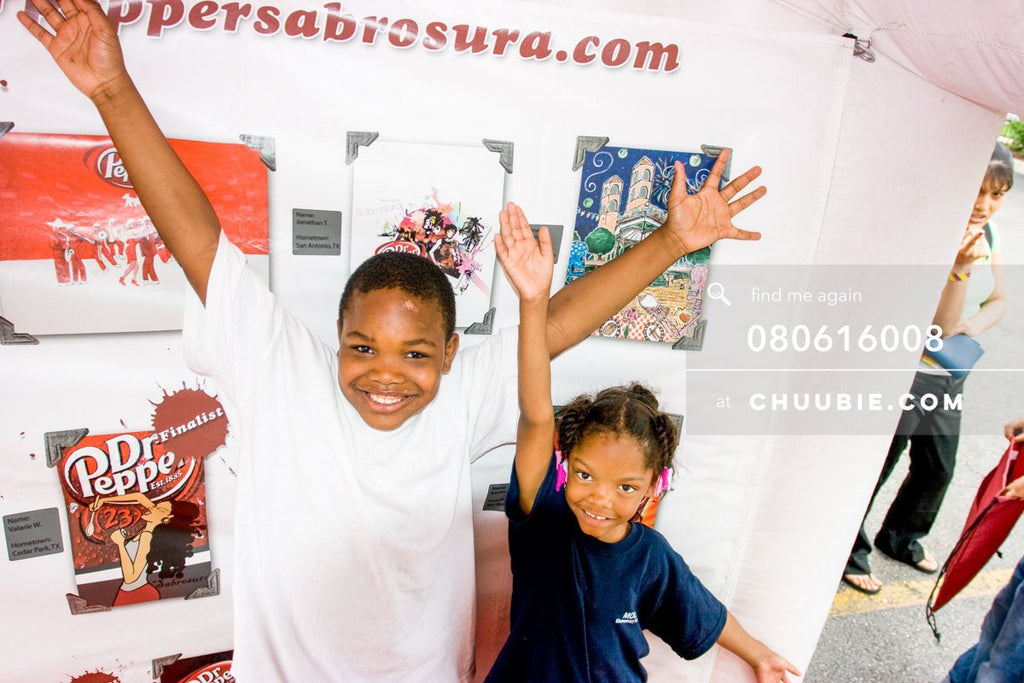 80613008 | 
Young boy and girl smile with arms up in air in front of the Sabrosura art contest winning piece... | Team Chuubie