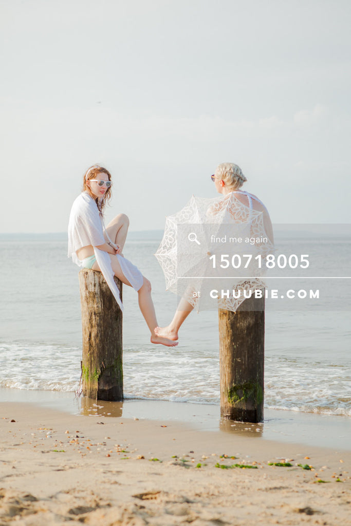 150718005 | 
Picturesque beach shot of two ladies in all-white beach gowns, sitting and conversing on wood pi... | Team Chuubie