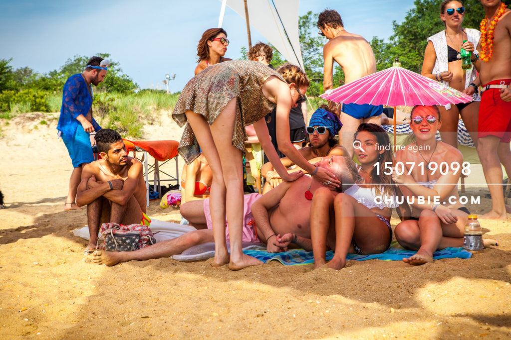 150719098 | 
Surfer girl and friends take shade under parasol at beach party.
—Gratitude Migration 2015: Summ... | Team Chuubie